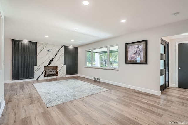 unfurnished living room with a fireplace and light wood-type flooring