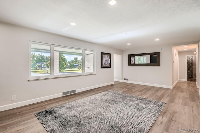 empty room with a textured ceiling and light hardwood / wood-style floors