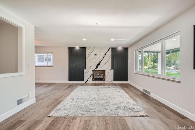 unfurnished living room with a textured ceiling, light hardwood / wood-style flooring, and a wealth of natural light