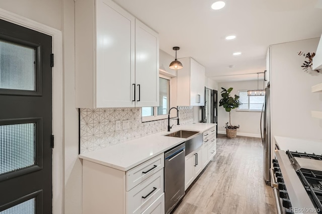 kitchen featuring hanging light fixtures, appliances with stainless steel finishes, sink, and white cabinets