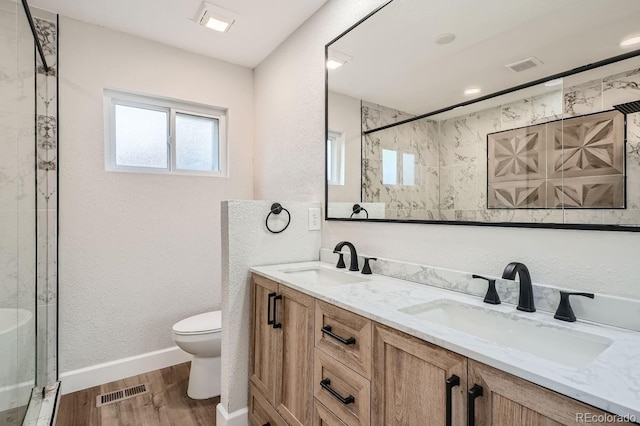 bathroom featuring tiled shower, wood-type flooring, toilet, and vanity