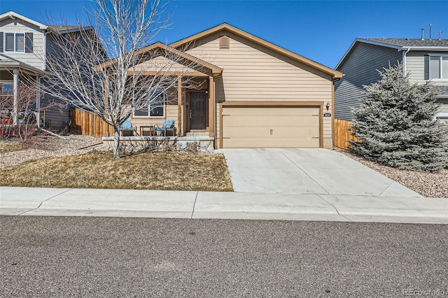 view of front facade with concrete driveway, an attached garage, and fence