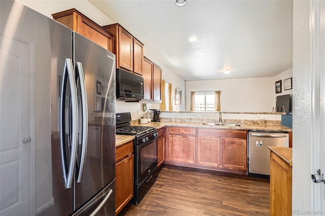 kitchen featuring brown cabinets, black appliances, a sink, light stone counters, and dark wood finished floors