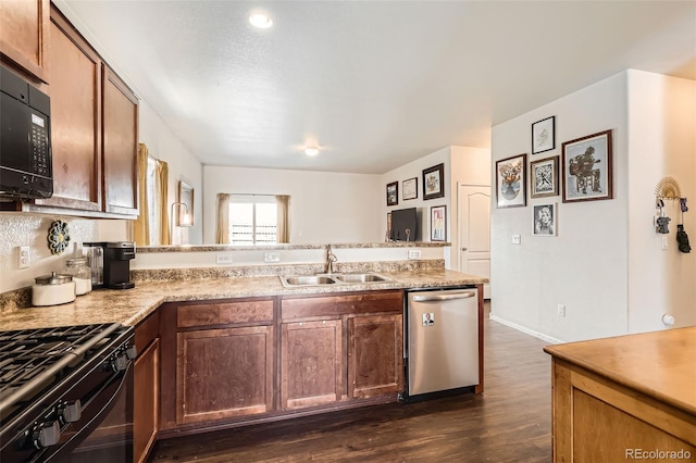 kitchen with a peninsula, black appliances, light countertops, and a sink