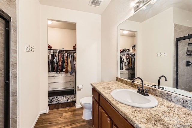 full bathroom with visible vents, a shower stall, toilet, wood finished floors, and vanity