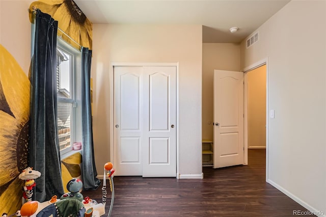 unfurnished bedroom with wood finished floors, visible vents, a closet, and baseboards