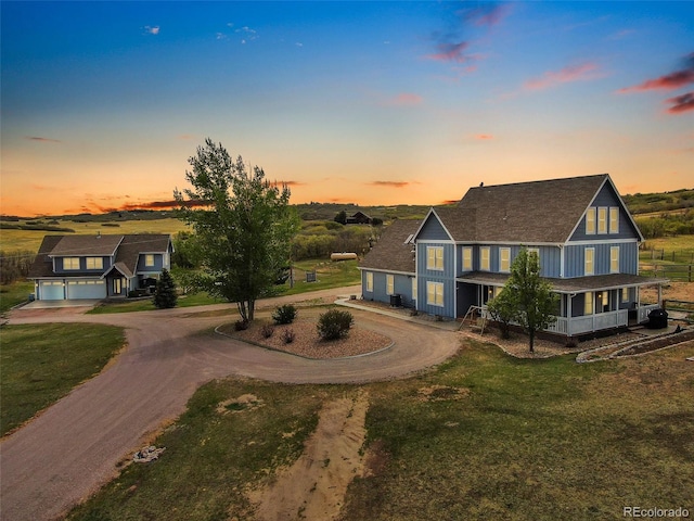 view of front of home with a porch, driveway, a garage, and a lawn