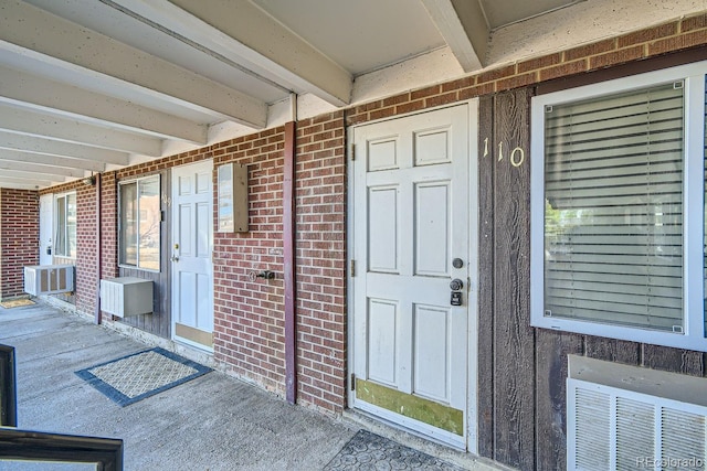 doorway to property with brick siding and visible vents