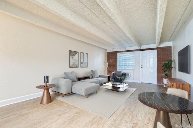 living room featuring beamed ceiling, a textured ceiling, baseboards, and wood finished floors