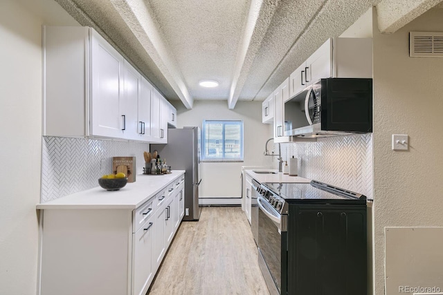 kitchen featuring light wood-style flooring, range with electric stovetop, visible vents, white cabinetry, and light countertops