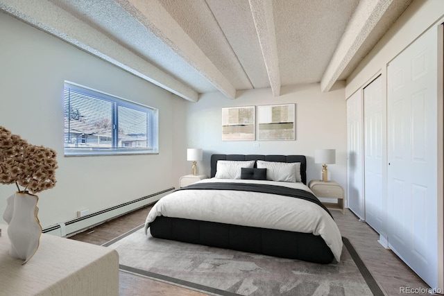 bedroom featuring a baseboard radiator, beamed ceiling, a textured ceiling, and wood finished floors