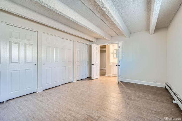 unfurnished bedroom with a textured ceiling, baseboard heating, wood finished floors, and beam ceiling