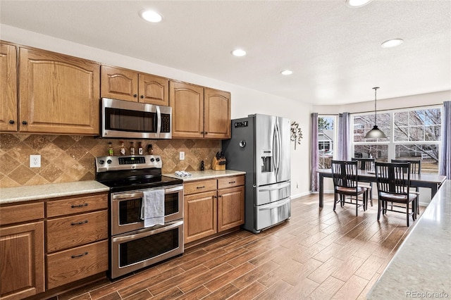 1128 S Duquesne Cir, Aurora, CO 80018 - kitchen with stainless steel appliances, light countertops, tasteful backsplash, brown cabinets, and recessed lighting