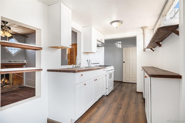 kitchen featuring dark hardwood / wood-style floors, ceiling fan, gas range gas stove, and white cabinets