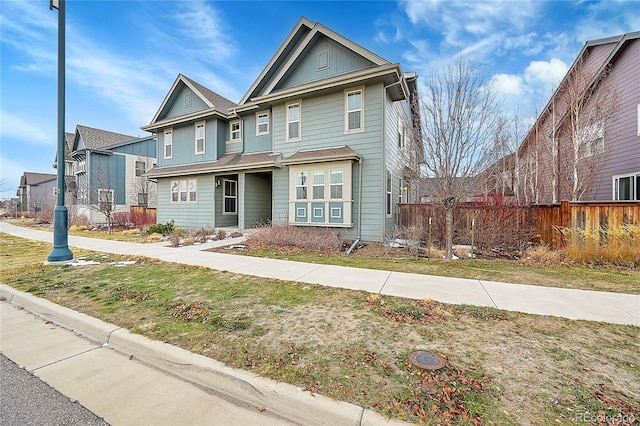 view of front of property with a front lawn, board and batten siding, and fence