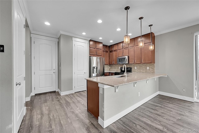 kitchen featuring light wood finished floors, a breakfast bar area, a peninsula, stainless steel appliances, and a sink