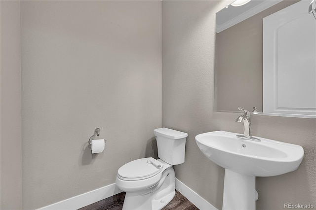 half bathroom featuring toilet, baseboards, and wood finished floors