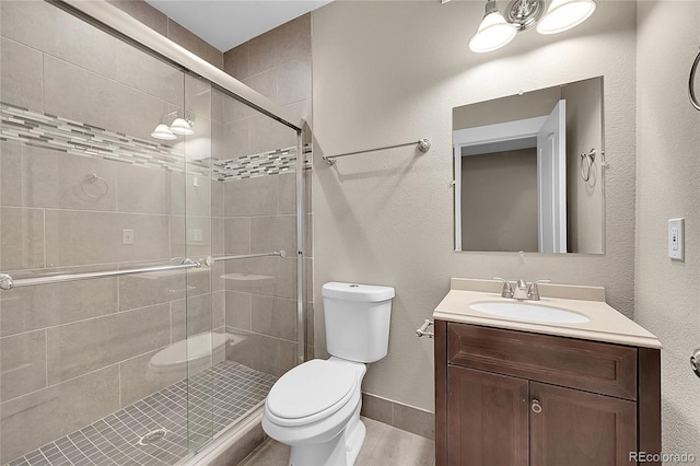 bathroom with baseboards, a shower stall, toilet, and vanity