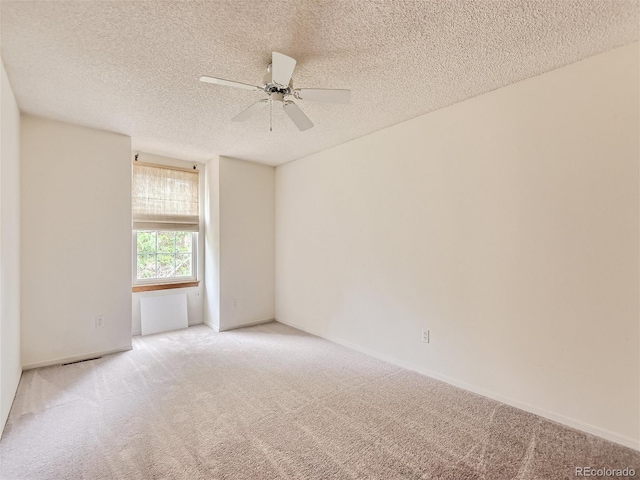 empty room with light carpet, ceiling fan, and a textured ceiling