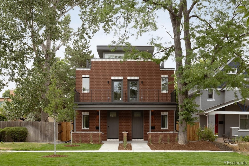 view of front of home featuring a balcony, a front yard, and covered porch