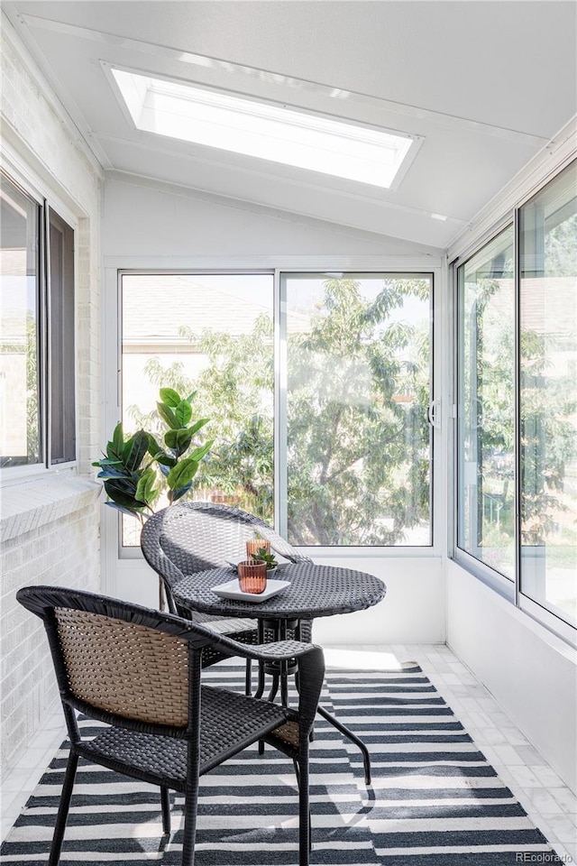 sunroom featuring vaulted ceiling with skylight