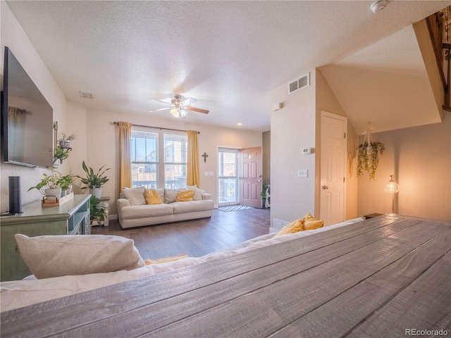 living room with ceiling fan, dark wood-type flooring, and a textured ceiling