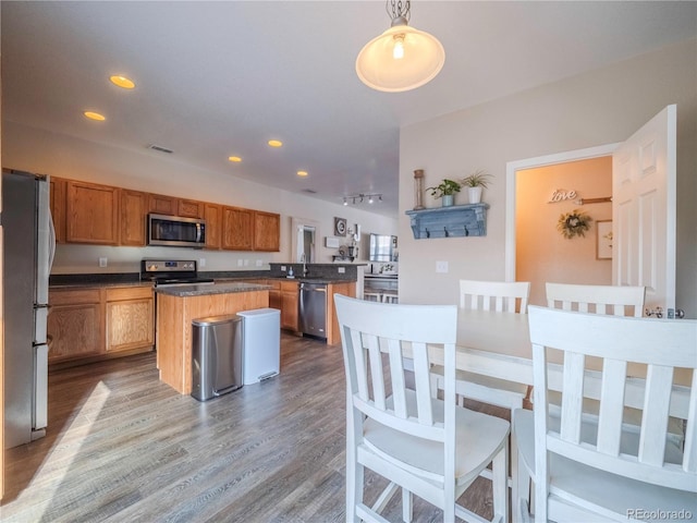 kitchen with pendant lighting, hardwood / wood-style floors, a kitchen island, stainless steel appliances, and sink