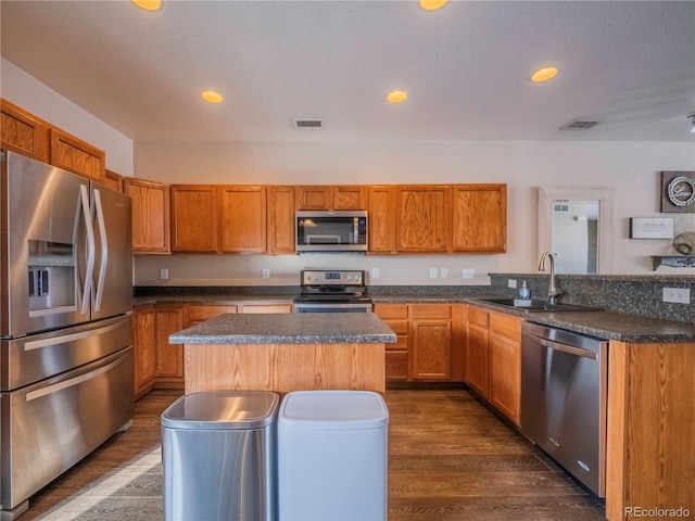 kitchen with sink, a center island, dark hardwood / wood-style floors, and appliances with stainless steel finishes