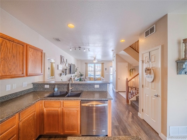 kitchen with a textured ceiling, dishwasher, sink, track lighting, and dark wood-type flooring