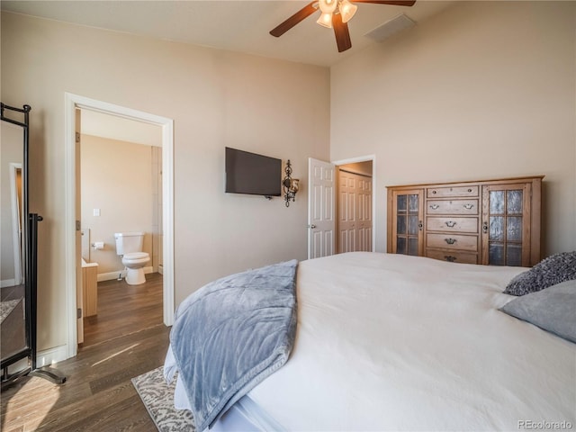 bedroom with ceiling fan, ensuite bathroom, dark hardwood / wood-style floors, and lofted ceiling