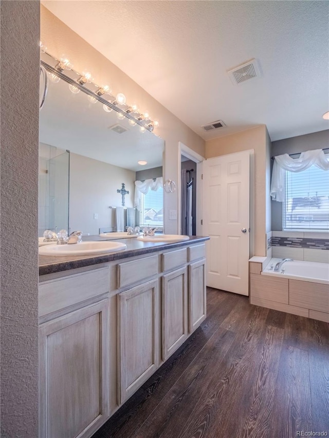 bathroom featuring vanity, hardwood / wood-style flooring, and tiled tub