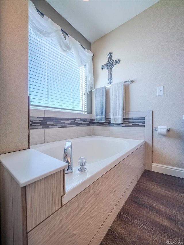 bathroom with hardwood / wood-style flooring and tiled tub