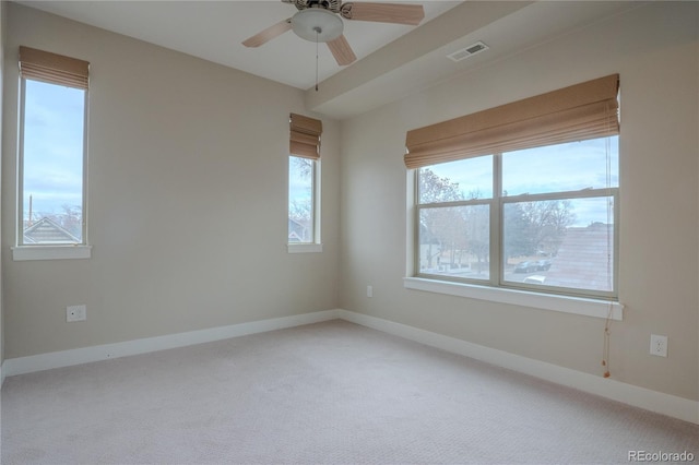 carpeted empty room with ceiling fan and a wealth of natural light