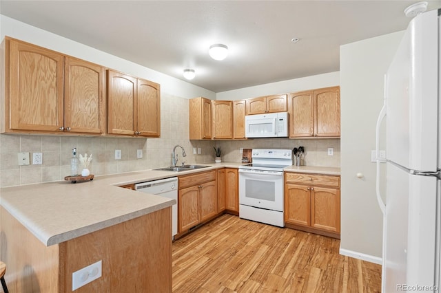 135 Carina Cir Unit 104, Loveland, CO 80537 - kitchen featuring white appliances, light wood finished floors, decorative backsplash, a peninsula, and light countertops