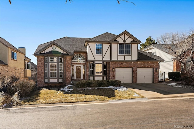 tudor house with a garage, brick siding, concrete driveway, roof with shingles, and stucco siding