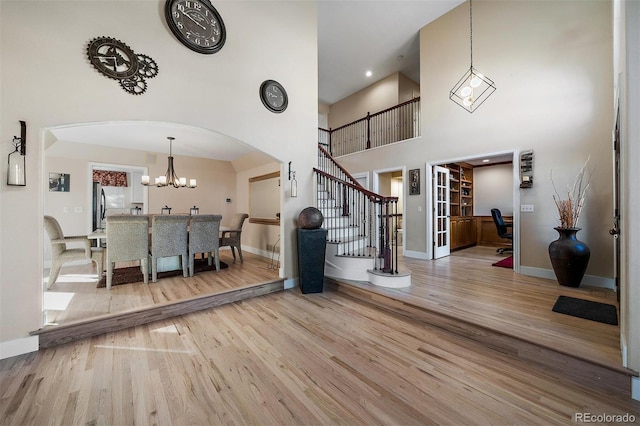 entrance foyer with a towering ceiling, baseboards, stairway, and wood finished floors