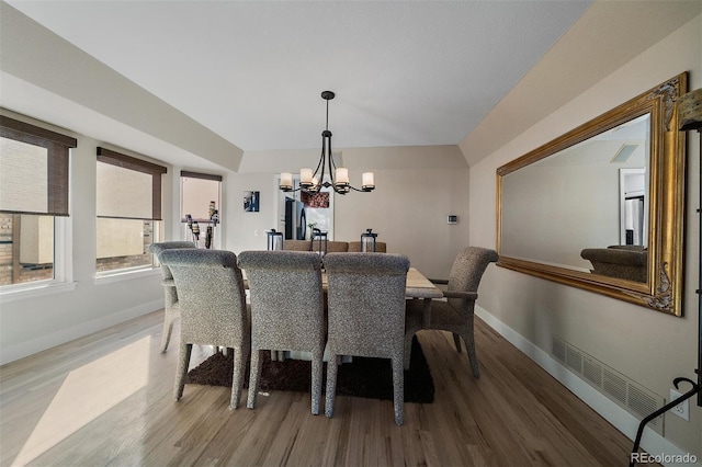 dining area featuring baseboards, wood finished floors, visible vents, and a notable chandelier