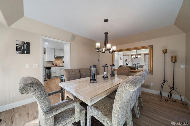 dining room featuring wine cooler, a notable chandelier, visible vents, baseboards, and light wood-style floors