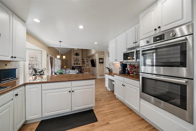 kitchen with stainless steel appliances, backsplash, light wood-style floors, white cabinetry, and a peninsula