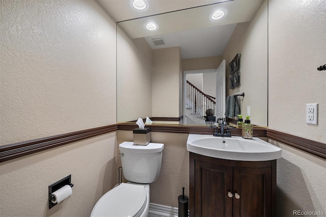 bathroom featuring a textured wall, toilet, recessed lighting, vanity, and visible vents