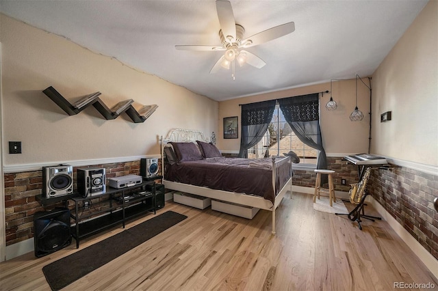 bedroom featuring a wainscoted wall, brick wall, a ceiling fan, light wood-style floors, and access to outside