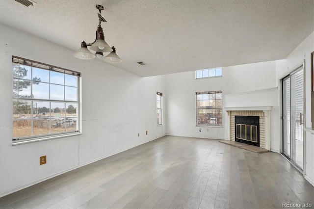 unfurnished living room featuring visible vents, a fireplace, a textured ceiling, and hardwood / wood-style floors