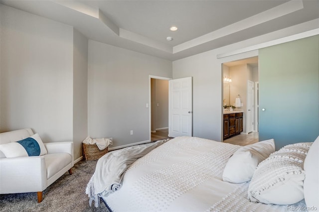 bedroom featuring a raised ceiling and connected bathroom