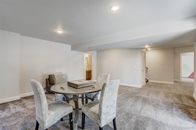 carpeted dining area featuring a textured ceiling