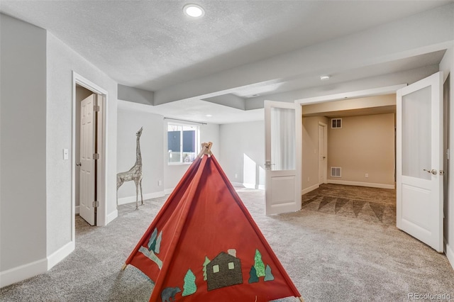 game room featuring a textured ceiling and light carpet