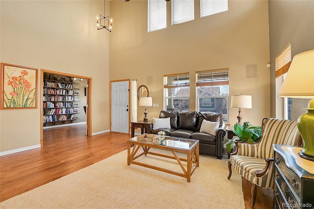 living area featuring a wealth of natural light, a chandelier, baseboards, and wood finished floors