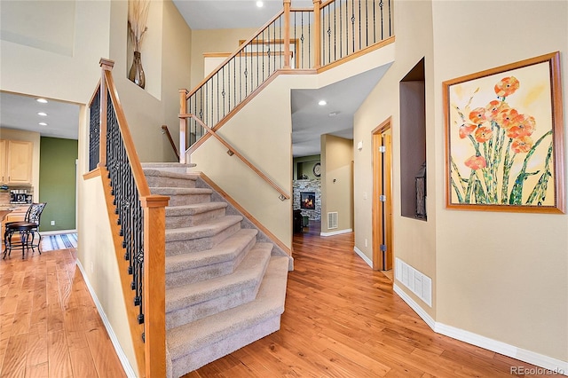 stairs with baseboards, a towering ceiling, and wood finished floors