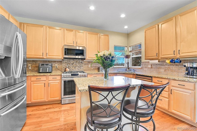 kitchen featuring light brown cabinetry, light wood-style flooring, stainless steel appliances, and a sink