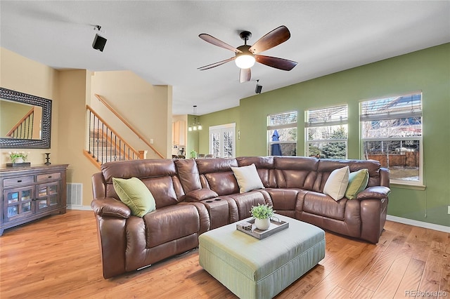 living room featuring a wealth of natural light, visible vents, light wood-style flooring, and stairway