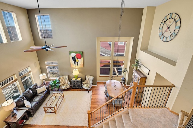 living area featuring stairs, a high ceiling, wood finished floors, and baseboards